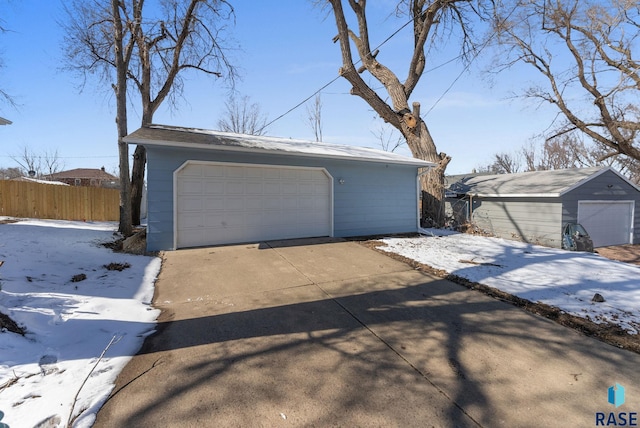 snow covered garage with a garage and fence