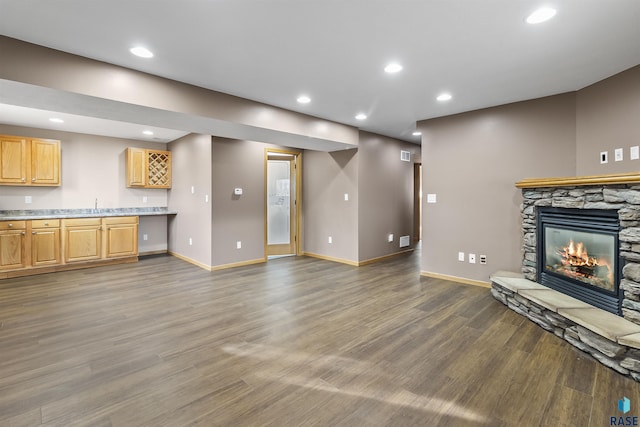 unfurnished living room with a stone fireplace, recessed lighting, wood finished floors, and baseboards