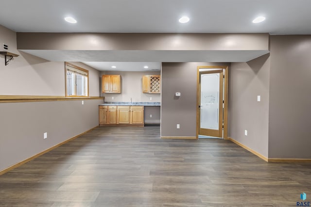 unfurnished living room with recessed lighting, indoor wet bar, baseboards, and dark wood finished floors