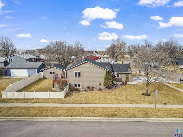 view of front facade featuring a front yard, fence, driveway, a garage, and a residential view