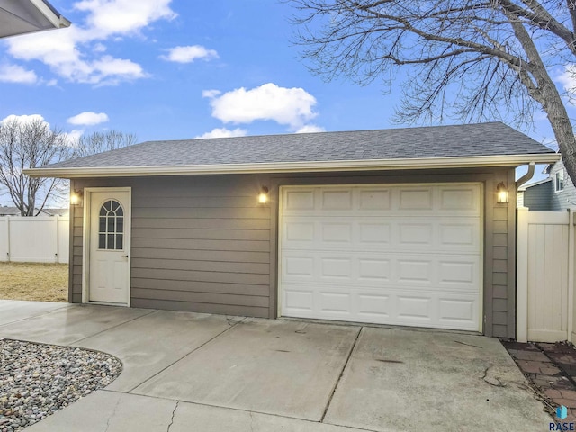 garage featuring concrete driveway and fence