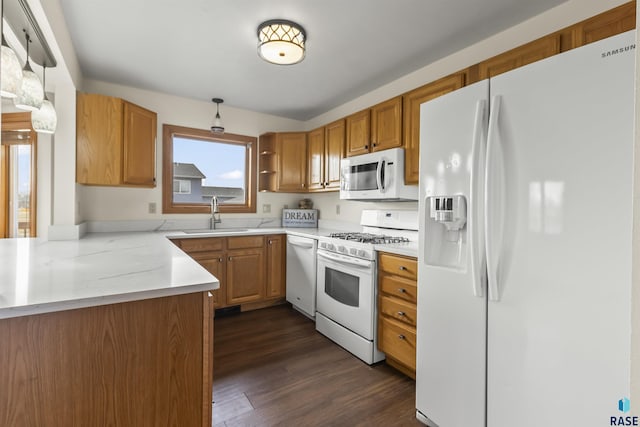 kitchen featuring white appliances, brown cabinets, dark wood-type flooring, and a sink