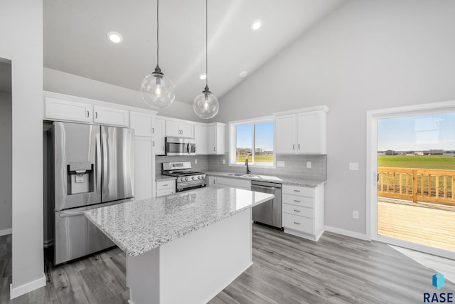 kitchen with tasteful backsplash, a center island, light stone counters, white cabinets, and stainless steel appliances