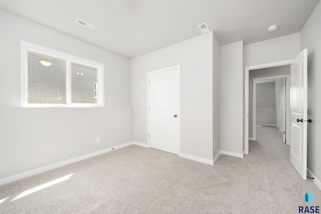 unfurnished bedroom featuring light colored carpet, visible vents, and baseboards