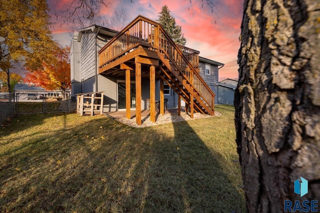 back of house featuring brick siding, fence, stairs, a deck, and a yard