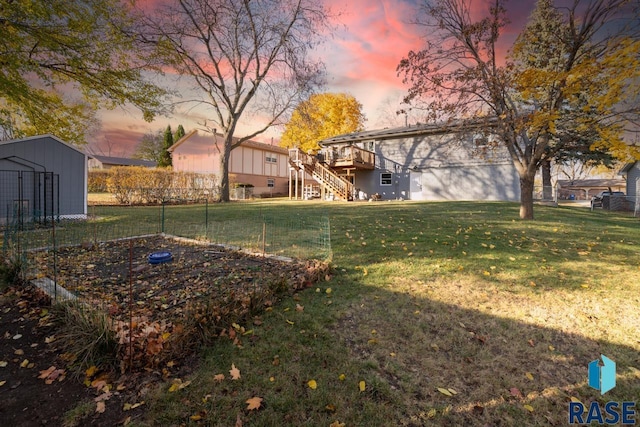 yard at dusk with a deck, fence, an outdoor structure, a garden, and stairs