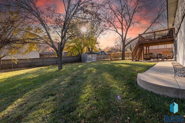 view of yard featuring a storage unit, an outbuilding, a deck, a fenced backyard, and stairs