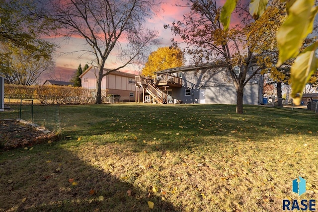 yard at dusk featuring a wooden deck, stairs, and fence