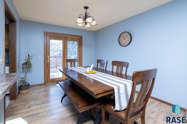 dining room with light wood-style floors, baseboards, and a chandelier