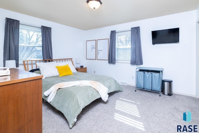 bedroom featuring visible vents, multiple windows, baseboards, and carpet