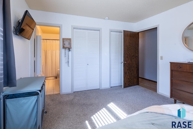 carpeted bedroom with connected bathroom and multiple closets