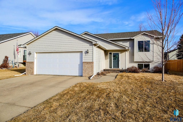 split level home featuring fence, driveway, roof with shingles, an attached garage, and brick siding