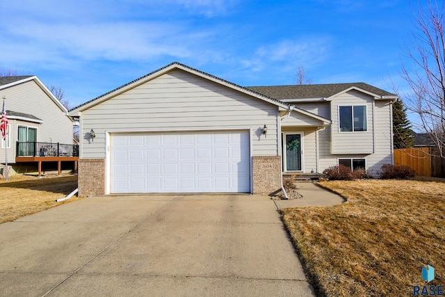 tri-level home with an attached garage, brick siding, and driveway