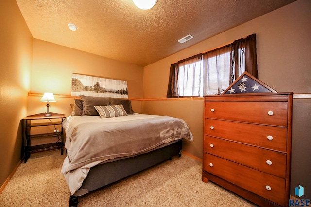 bedroom featuring visible vents, light colored carpet, a textured ceiling, and baseboards