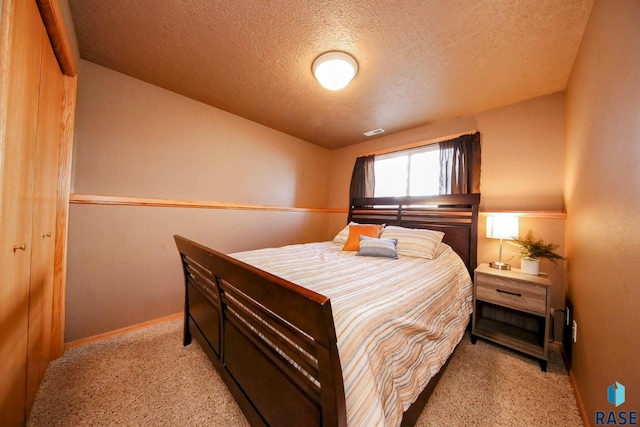 carpeted bedroom featuring visible vents, a textured ceiling, and baseboards