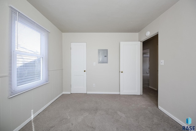 unfurnished bedroom featuring electric panel, baseboards, and carpet floors