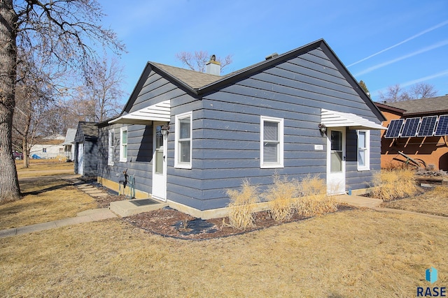 view of front of property with a front lawn, a chimney, and roof with shingles