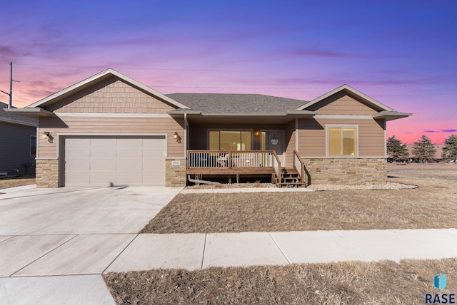 craftsman-style home featuring concrete driveway, an attached garage, covered porch, and stone siding