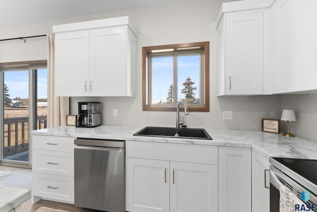 kitchen featuring a sink, light stone counters, stainless steel dishwasher, and white cabinets