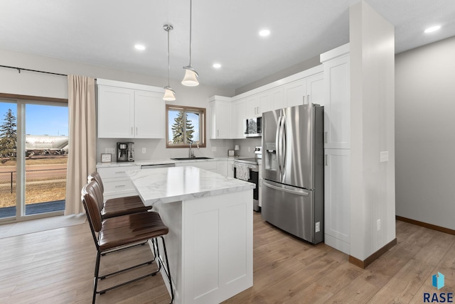 kitchen with light wood-style flooring, appliances with stainless steel finishes, a center island, and a sink