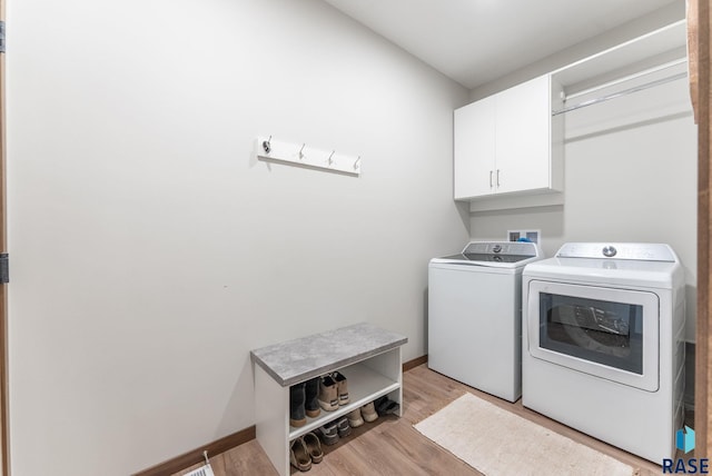 laundry room featuring baseboards, cabinet space, light wood-type flooring, and washer and clothes dryer