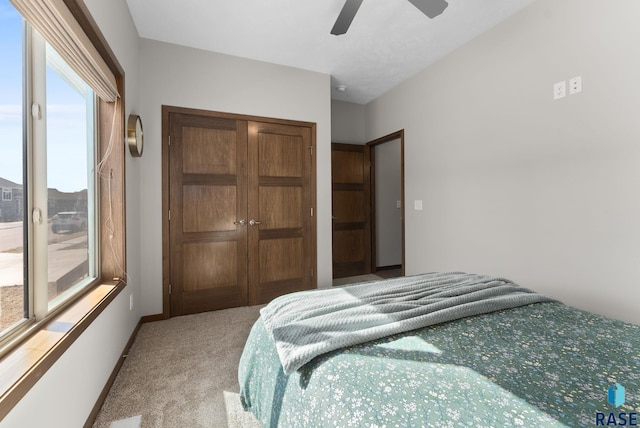 bedroom with light colored carpet, baseboards, a closet, and ceiling fan