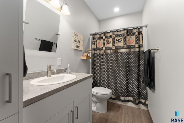 full bathroom featuring curtained shower, toilet, vanity, and wood finished floors