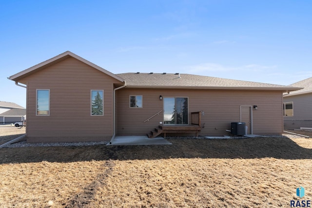 back of house featuring entry steps, central AC unit, a yard, and fence