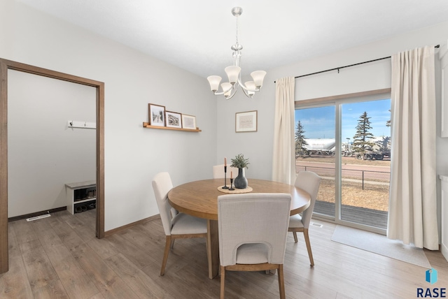 dining space featuring light wood-style floors, baseboards, and a chandelier