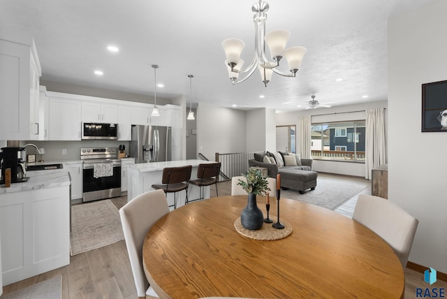 dining room with recessed lighting, ceiling fan with notable chandelier, and light wood-type flooring