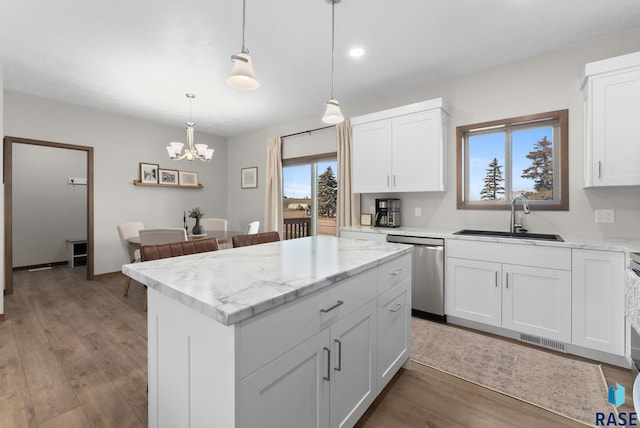 kitchen with wood finished floors, visible vents, a sink, dishwasher, and a center island