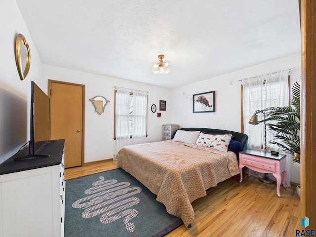 bedroom featuring multiple windows and light wood-style floors