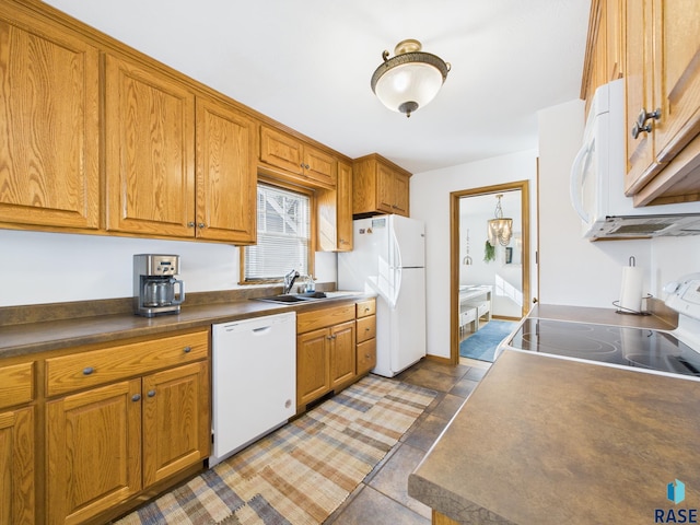 kitchen with brown cabinetry, white appliances, dark countertops, and a sink