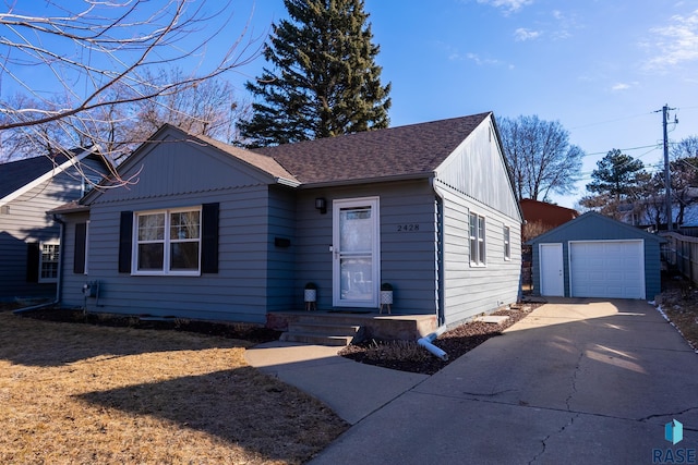 ranch-style home featuring a detached garage, roof with shingles, an outdoor structure, and concrete driveway