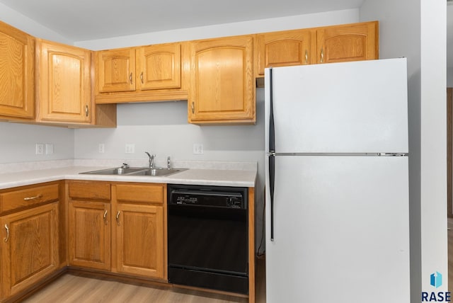 kitchen with light countertops, black dishwasher, freestanding refrigerator, and a sink