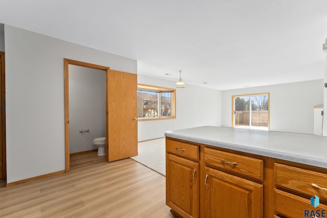 kitchen with light wood finished floors, brown cabinets, light countertops, and baseboards