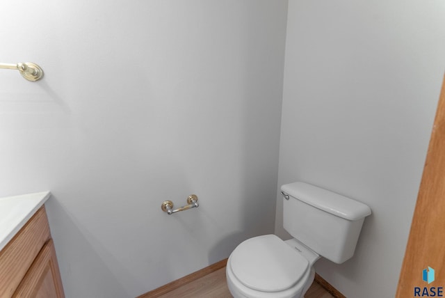 bathroom featuring toilet, vanity, and baseboards