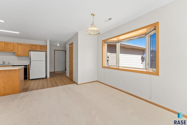 kitchen featuring baseboards, decorative light fixtures, light countertops, light carpet, and freestanding refrigerator