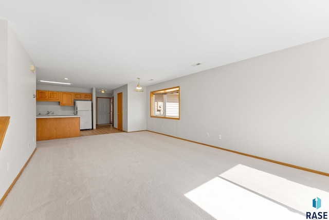 unfurnished living room with light colored carpet and baseboards