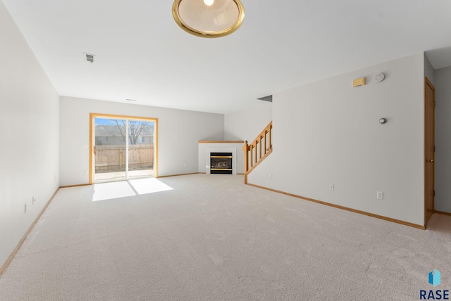 unfurnished living room featuring visible vents, a fireplace, baseboards, and carpet