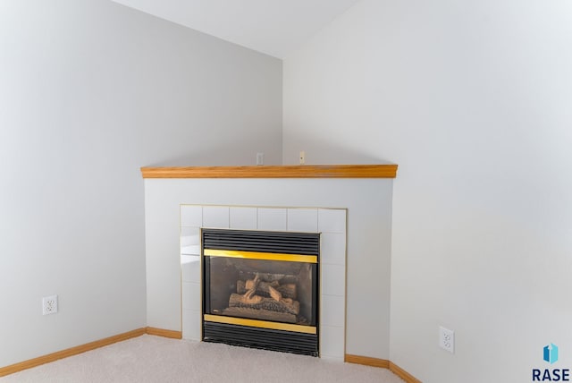 interior details featuring a tile fireplace, baseboards, and carpet