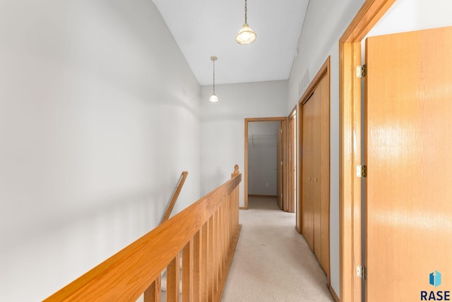 corridor featuring an upstairs landing and light carpet