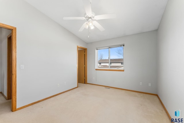 carpeted spare room featuring lofted ceiling, visible vents, baseboards, and ceiling fan