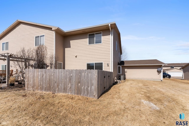 rear view of property featuring central air condition unit and fence