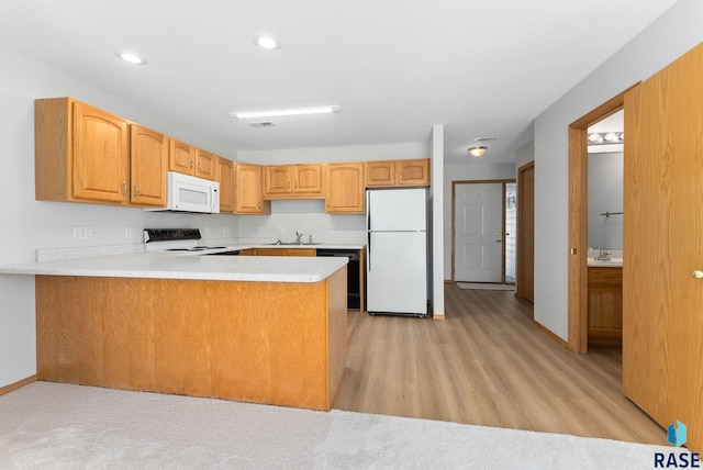 kitchen featuring a sink, recessed lighting, white appliances, a peninsula, and light countertops