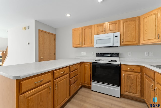 kitchen featuring white microwave, range with electric cooktop, light countertops, light wood-type flooring, and a peninsula