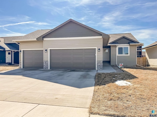 ranch-style house with fence, roof with shingles, an attached garage, concrete driveway, and stone siding