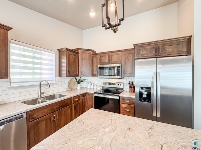 kitchen with decorative backsplash, light stone countertops, stainless steel appliances, and a sink