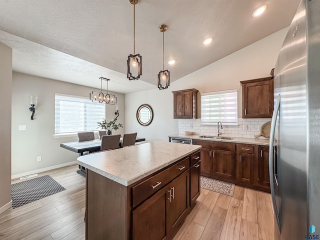 kitchen with a sink, backsplash, a center island, stainless steel appliances, and light countertops