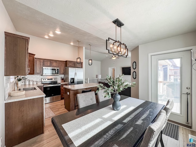 dining space with an inviting chandelier, light wood finished floors, and a textured ceiling